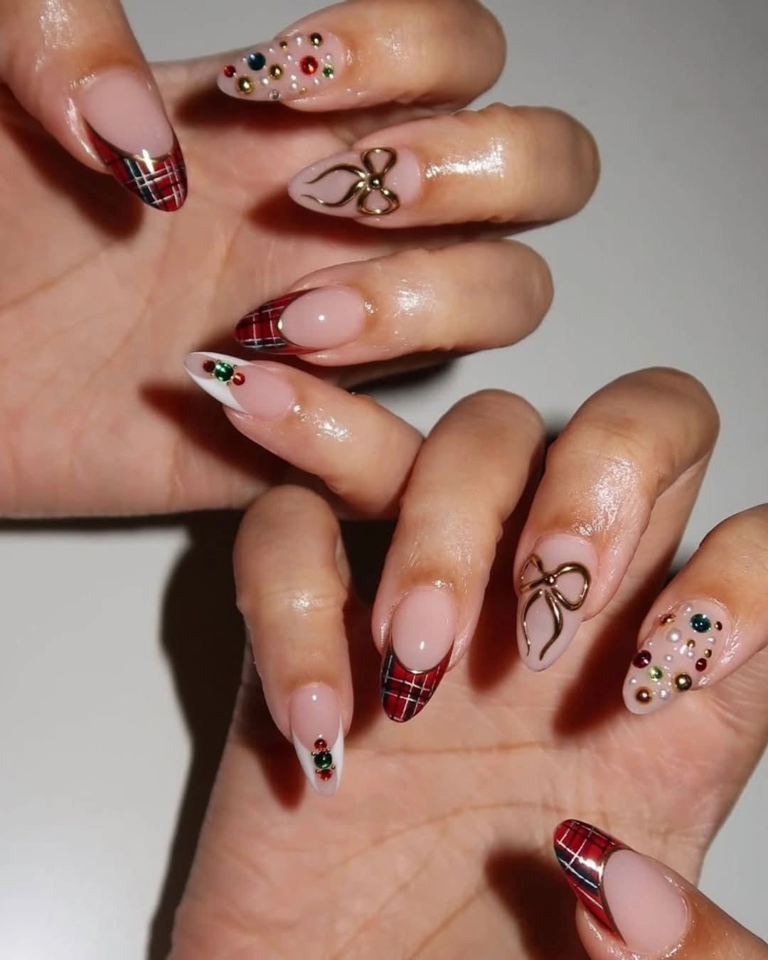 Long almond nails with red plaid tips, metallic bows and colorful raised embellishments.