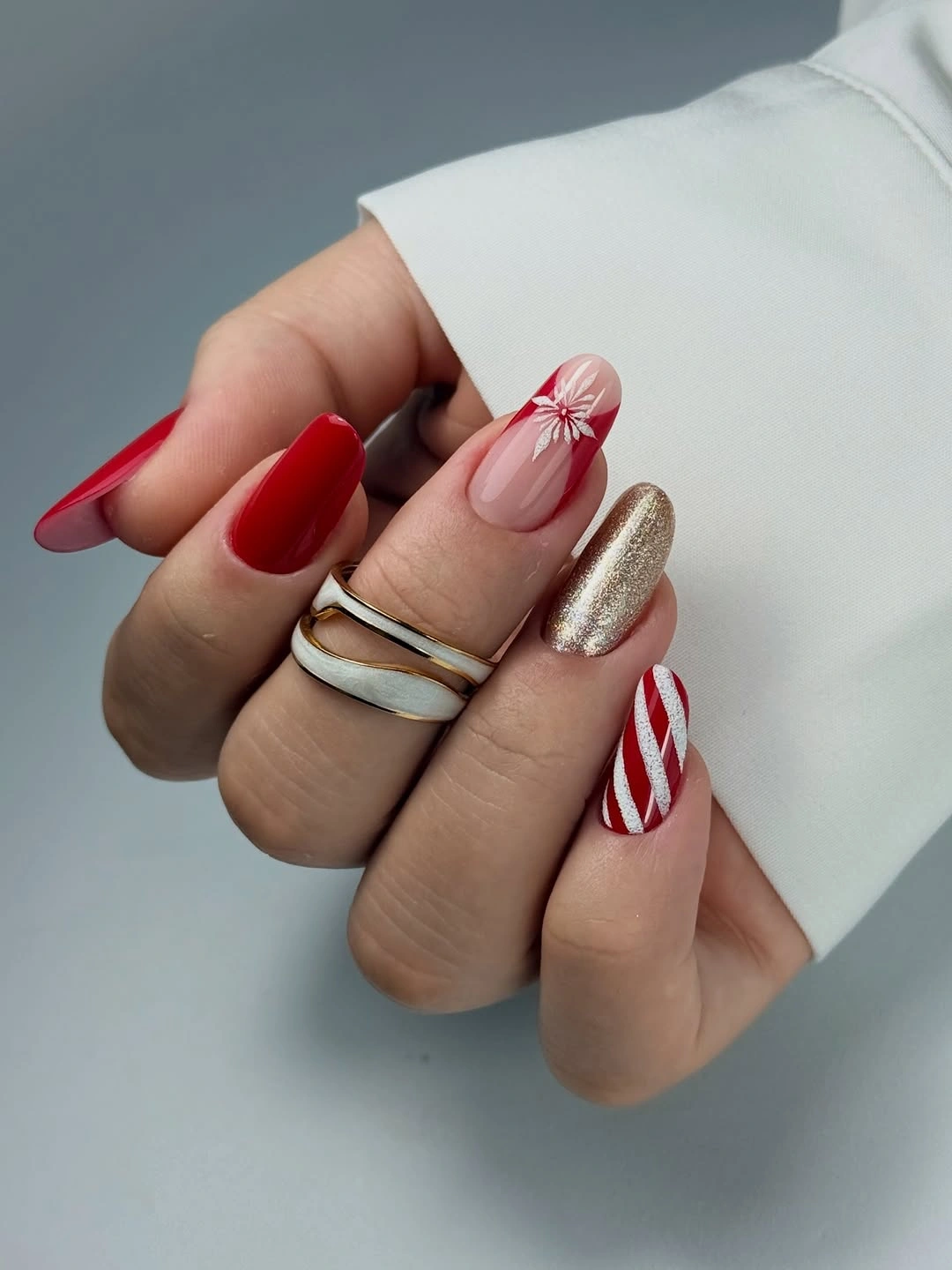 Red almond nails with gold glitter, candy cane stripes and a red starburst.