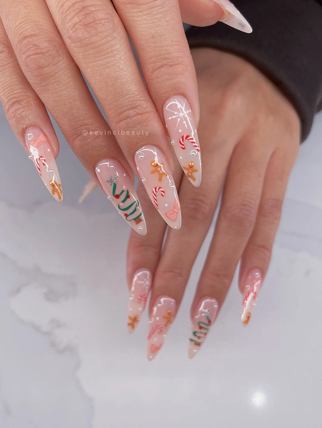Long pointed pink nails with candy canes, Christmas trees and colorful holiday doodles.
