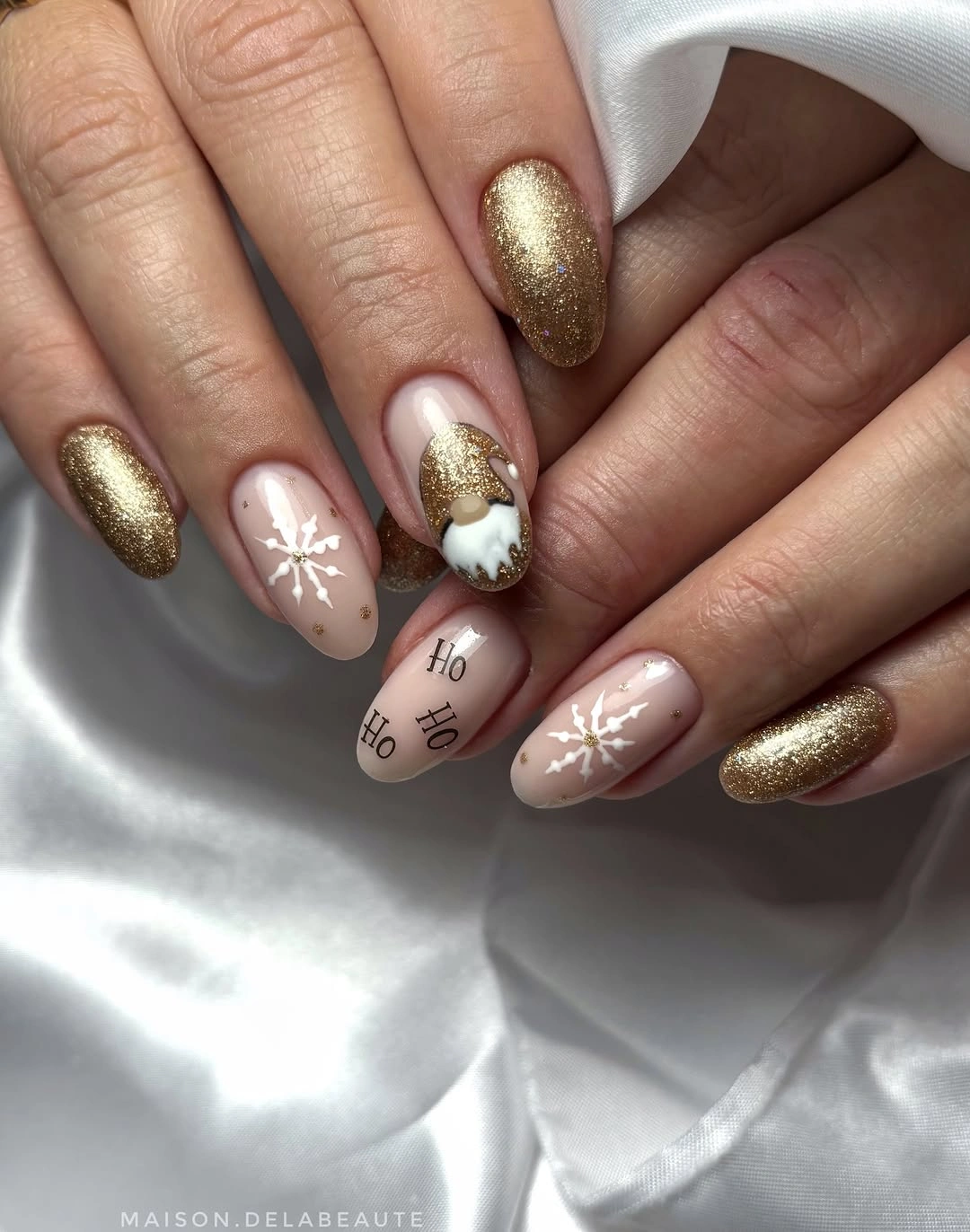 Gold glitter almond nails with white snowflakes, holiday lettering and winter illustrations.