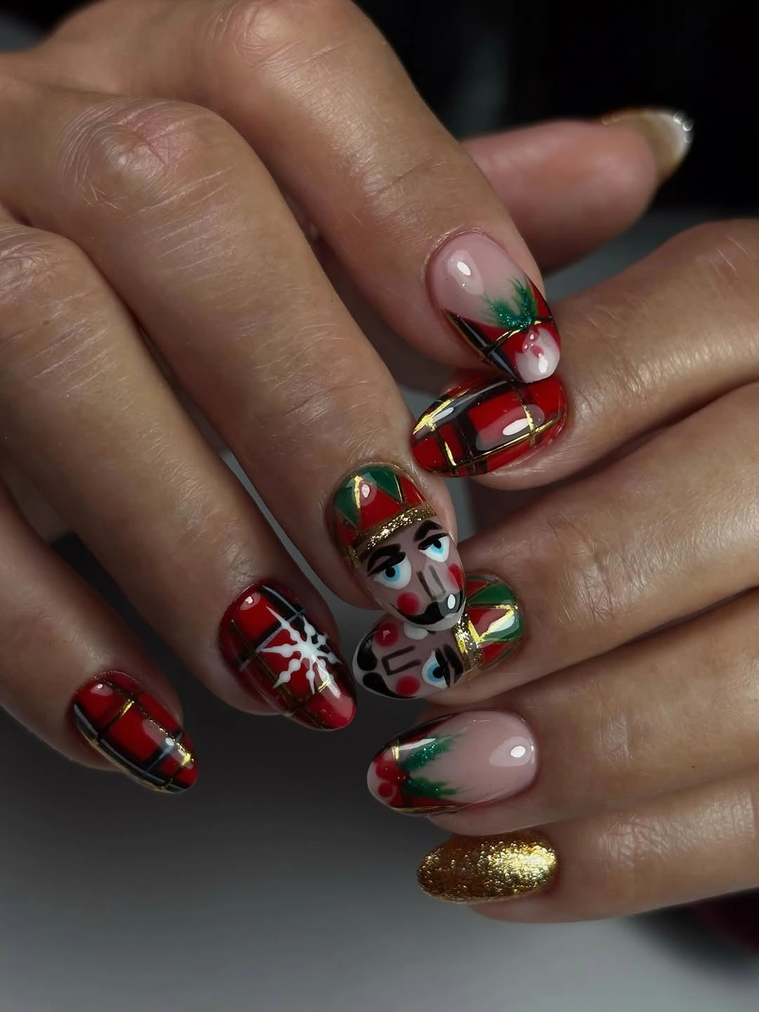 Christmas nails with painted holiday character, red tartan, green details and gold glitter.