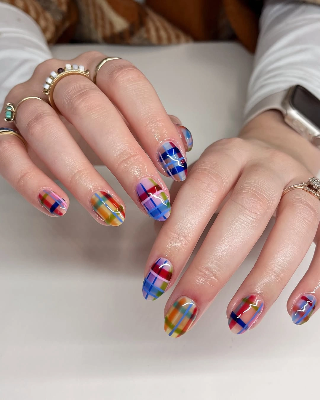 Oval nails with multicolored plaid patterns in blue, red, green and yellow.