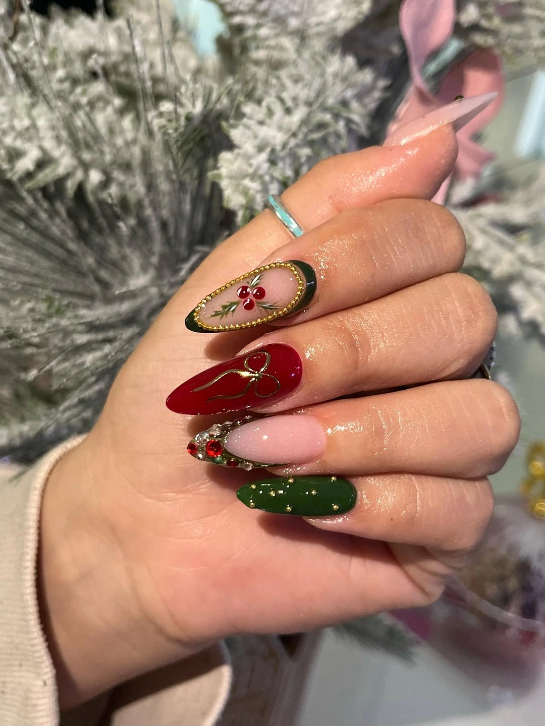 Long red and green nails with gold outlines and colorful jewel-like accents.