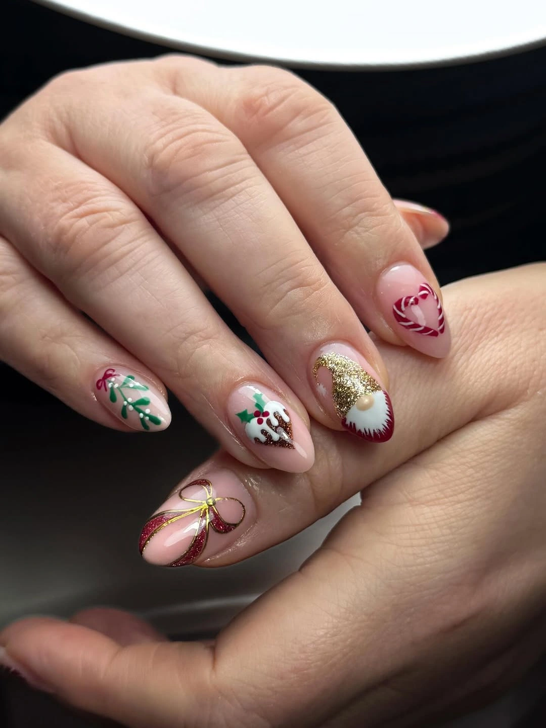 Pink almond nails with candy cane heart, greenery, gold glitter and ribbons.