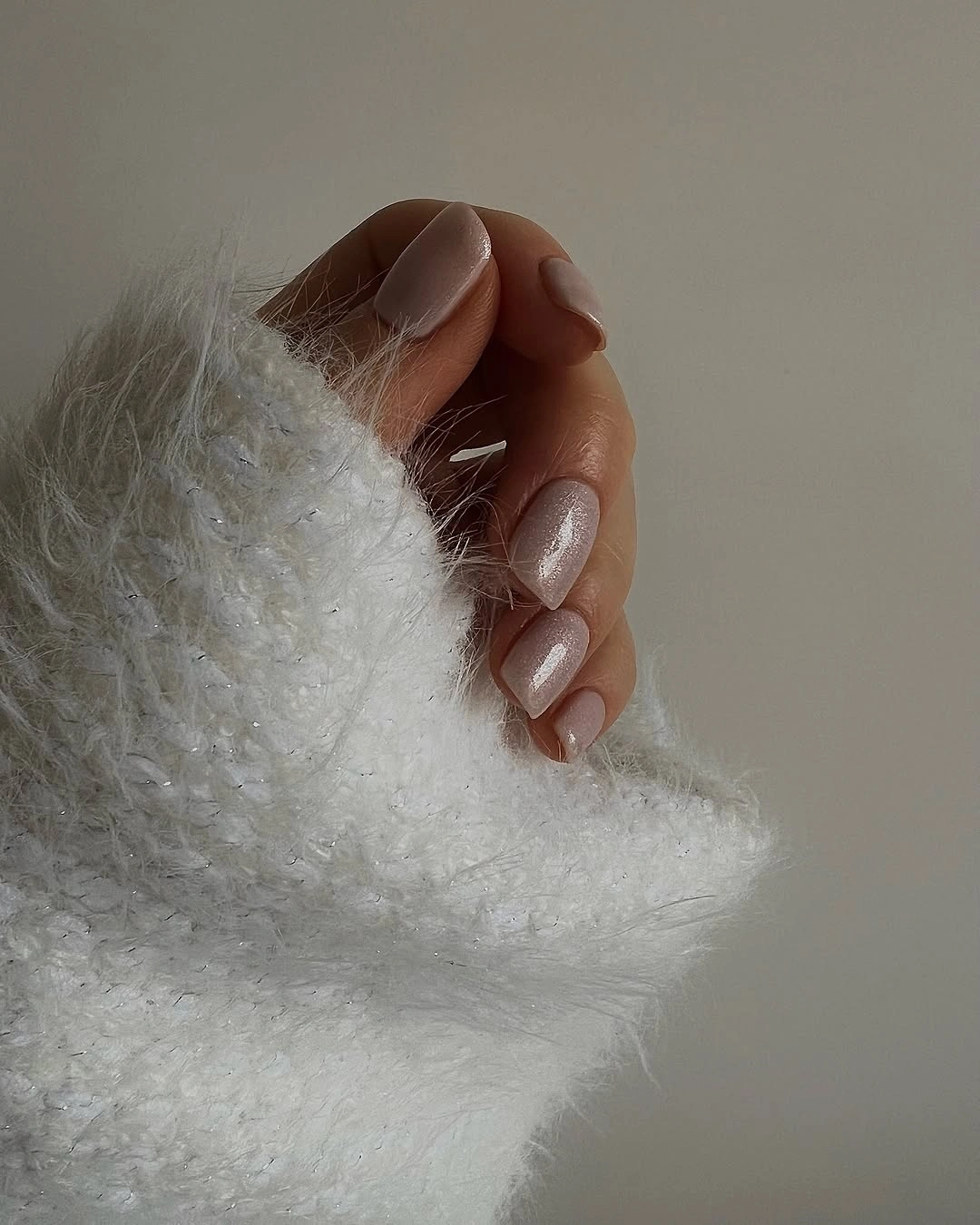 Short rounded nails with subtle champagne beige shimmer and a smooth reflective finish.