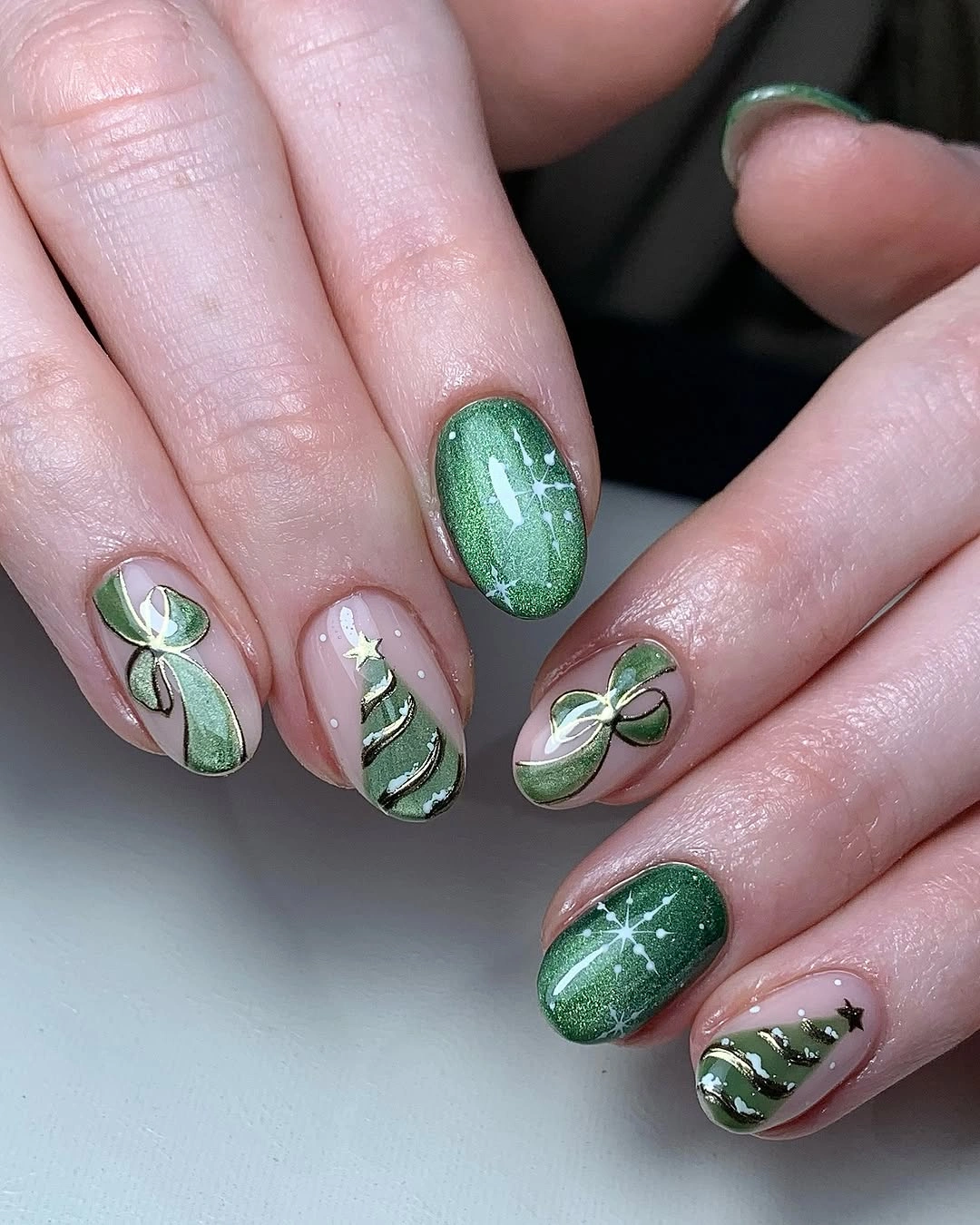 Emerald green oval nails with ribbon bows, Christmas trees and white star accents.