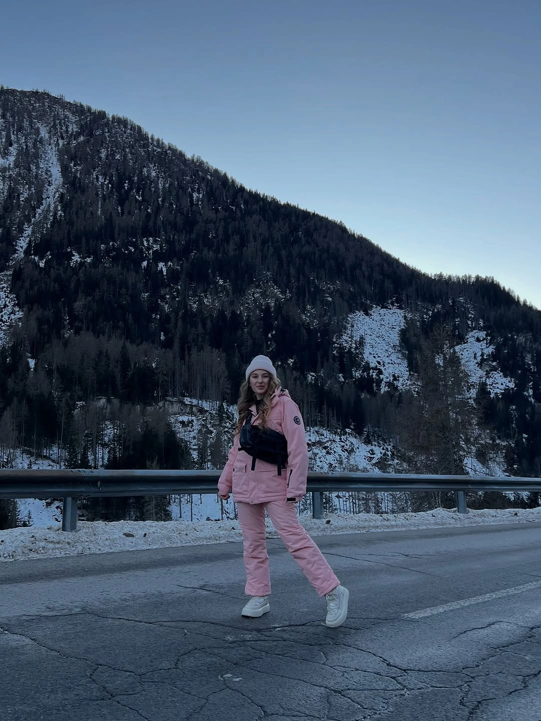 Matching pink winter jacket and pants with white beanie and sneakers.