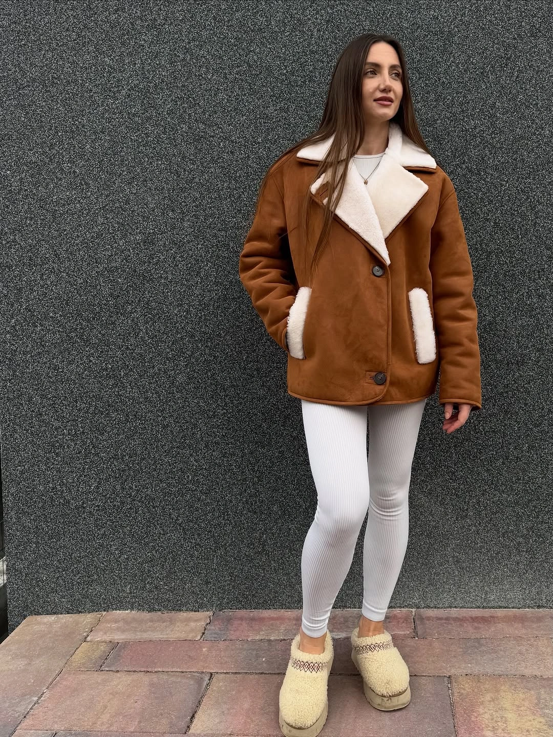 Cognac brown jacket with white plush lapels, fitted pants, and cream slippers.