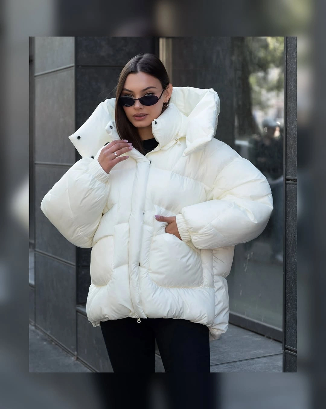 Oversized white puffer jacket with dramatic collar, black pants, and sunglasses.