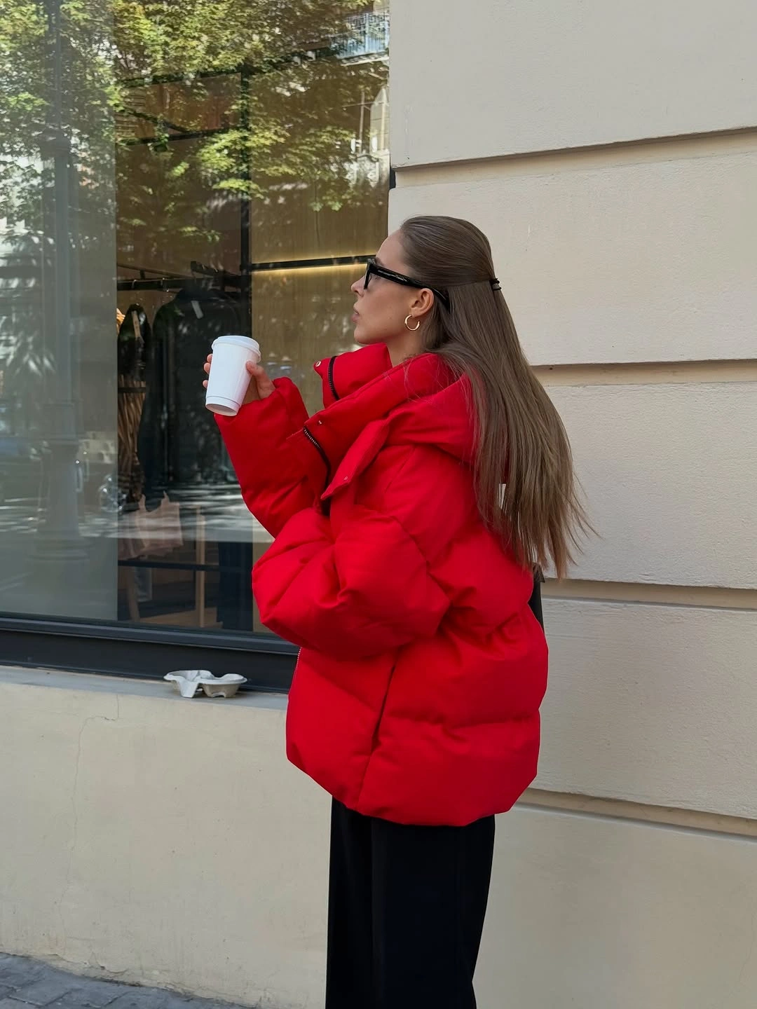 Bright red oversized puffer jacket with black pants and dark sunglasses.