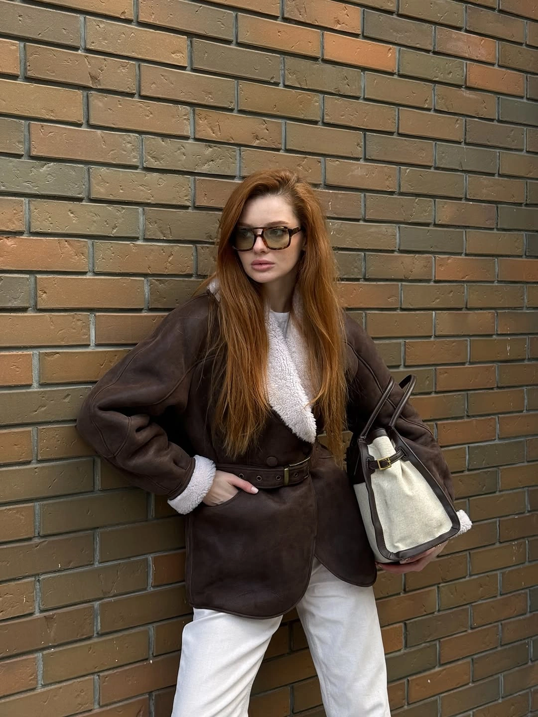 Chocolate brown belted jacket with white plush trim and white trousers.