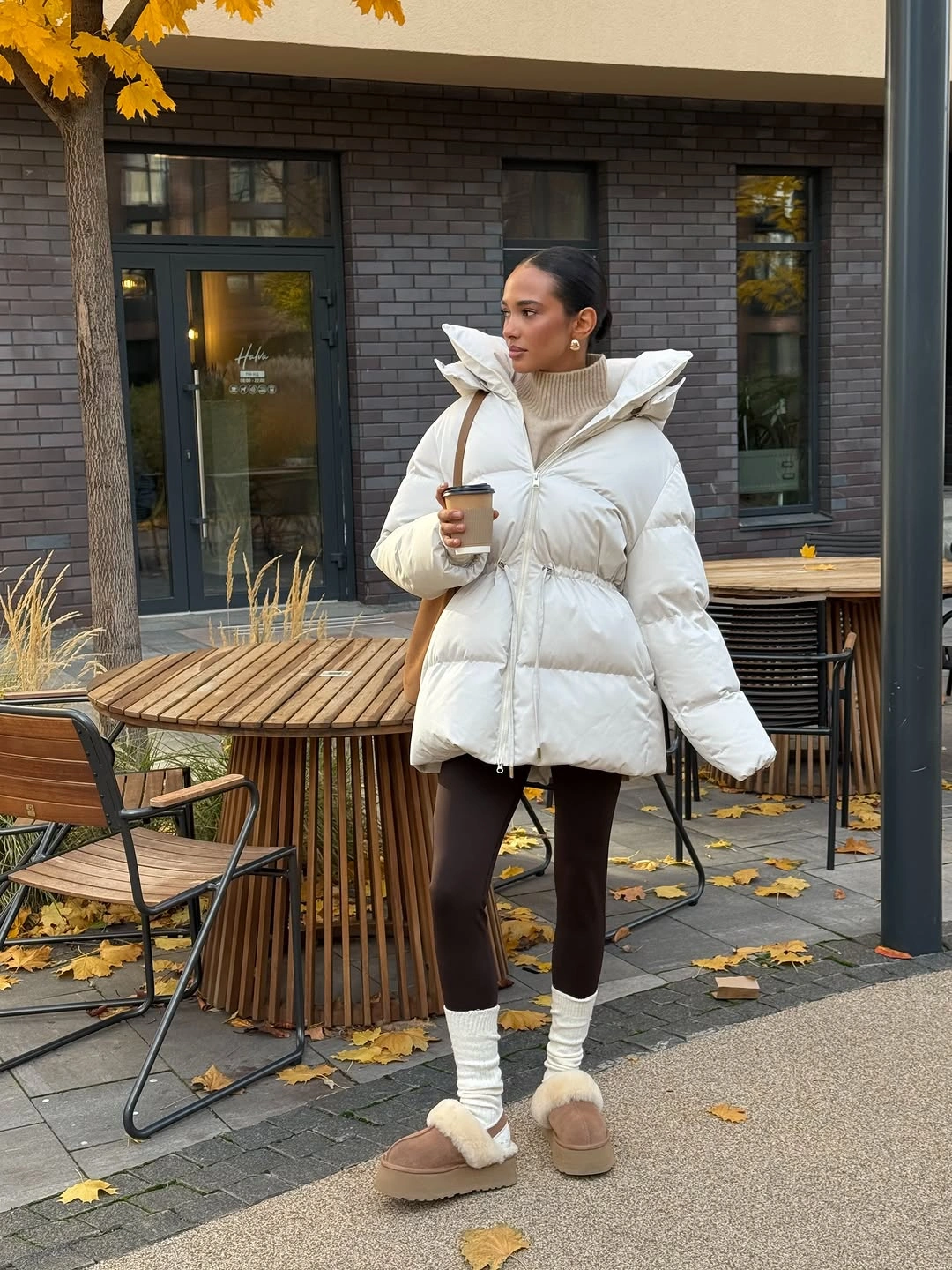 White belted puffer jacket with brown leggings, cream leg warmers, and plush slippers.