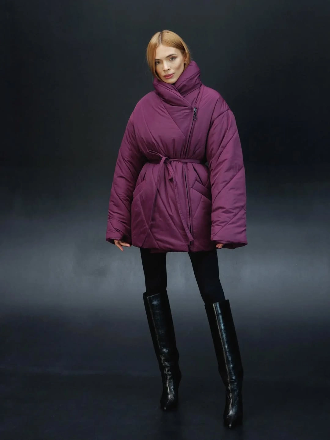 Deep berry purple belted padded jacket with black pants and tall boots.